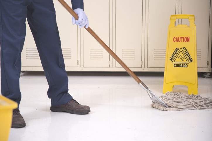 Person mopping a floor in a school hallway.
