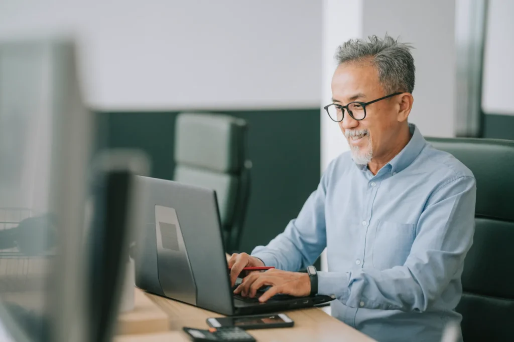 Smiling man types on laptop computer.